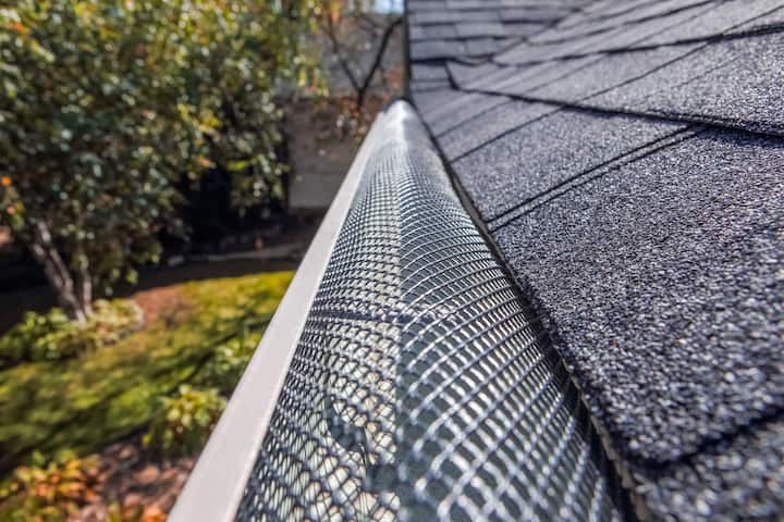 A contractor demonstrating the effectiveness of a gutter guard to a potential client in Katy